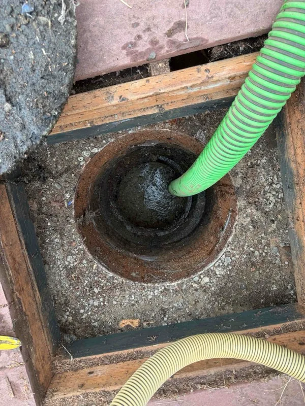 Looking down through the opening in the deck at the septic lid below, with the suction hose running into the tank.