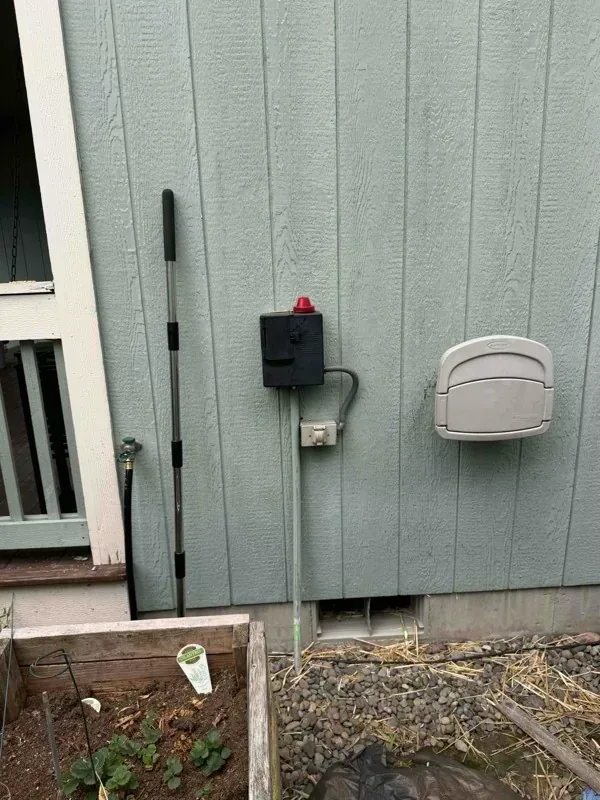 The septic alarm panel and its red beacon light, mounted on the exterior wall of the house.