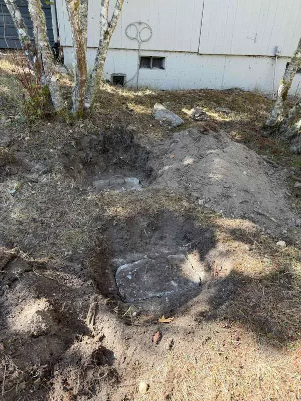 Both tank lids exposed after excavation, with the spoil piled alongside.