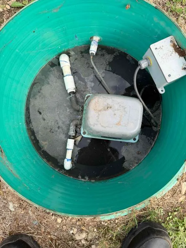 The pump tank opened up, showing the pump, the float switches and the junction box.