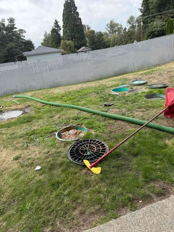 The work area in the back garden, with the suction hose run across the lawn and the riser lids for all three tanks uncovered.