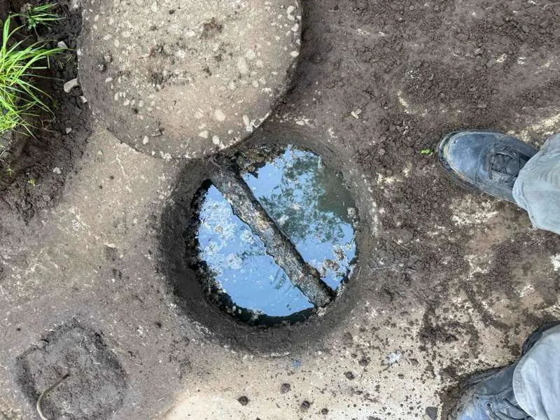 The access opening uncovered, with the lid set aside on the ground.
