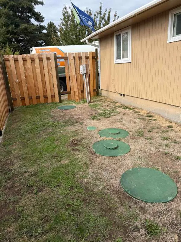 The work area in the back garden, with the riser lids for both tanks uncovered and the truck drawn up beyond the fence.