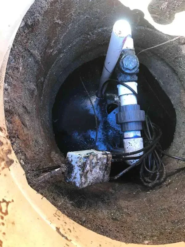 Looking down into the pump tank riser at the pump plumbing, its union and the wiring.