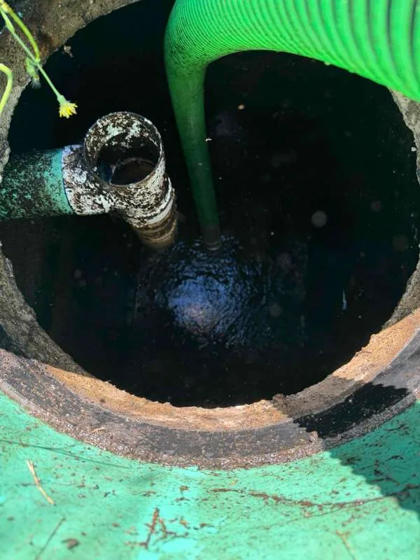 The suction hose lowered past the inlet pipe to pump the trash tank.