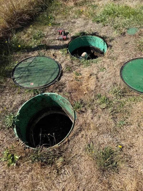 Risers opened for inspection, with the lids set aside on the grass.