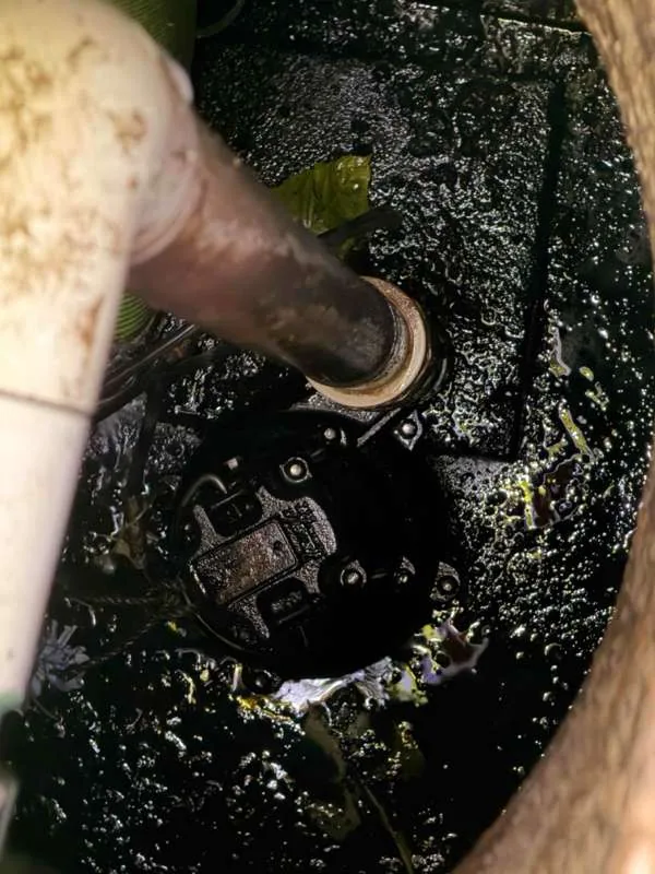 Looking down into the pump tank at the pump and its discharge pipe.