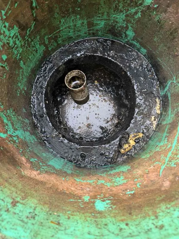 A compartment drawn down after pumping, with the pipe stub clear of the liquid.