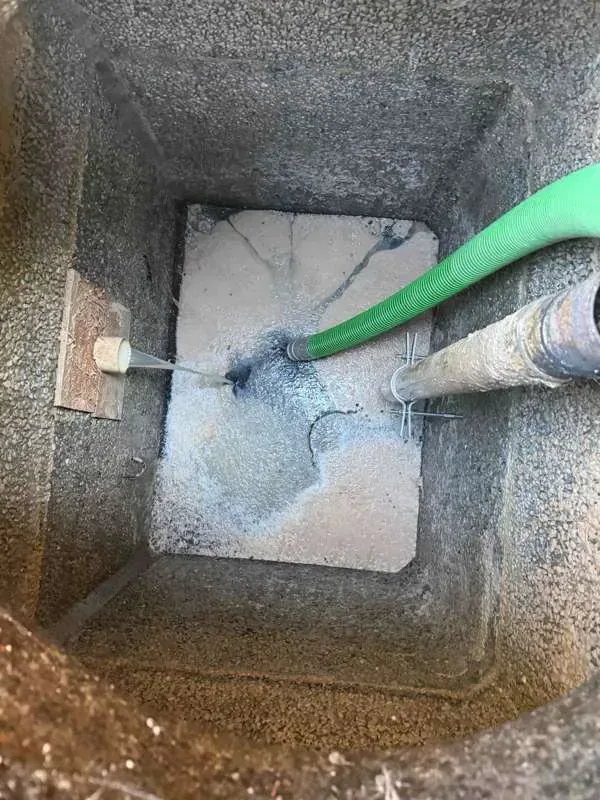 Looking down into a compartment during pumping, with the suction hose in place and a pipe entering at the wall.