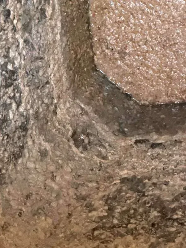 A close view of the tank wall showing cracked and deteriorating concrete.