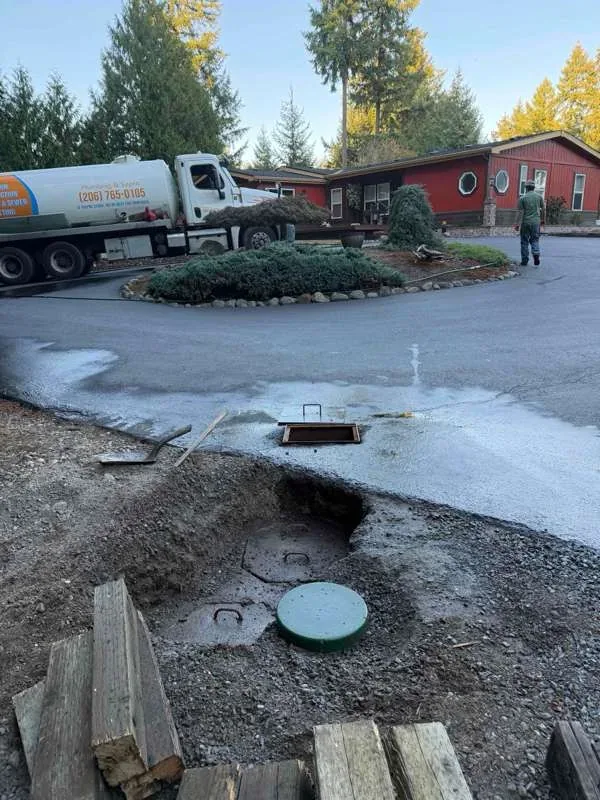 The vacuum truck on the driveway, with the tank lids opened in the foreground.