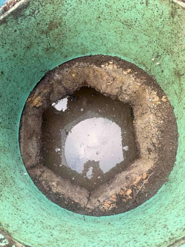 Looking down inside a riser to the tank lid below, with the joint between them open around its whole circumference.