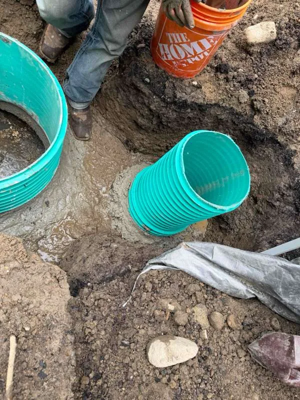 A riser section set down beside the wet concrete before being fitted.
