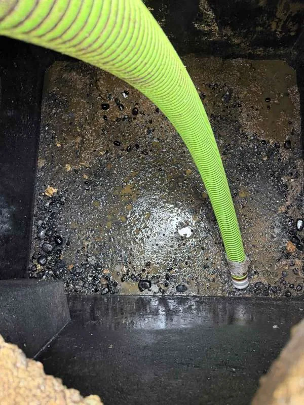 Pumping a compartment out, with the dividing wall of the two-compartment tank visible behind the hose.