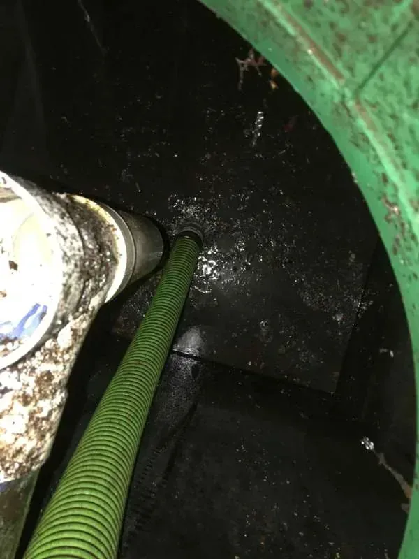 The suction hose down in the tank alongside the inlet pipe during pumping.