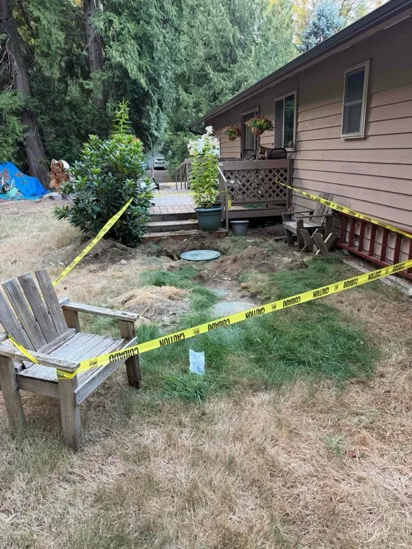 The work area taped off beside the deck, with the ground opened up around the chamber.