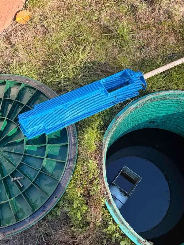 The effluent filter laid out on the grass between the open riser and its lid.