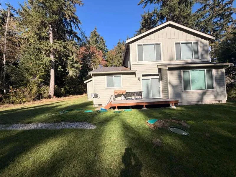 The back of the house, with the green riser lids set flush in the lawn across the yard.