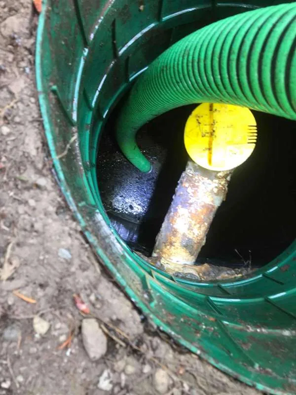 The suction hose fed down into the riser beside the capped pipe.