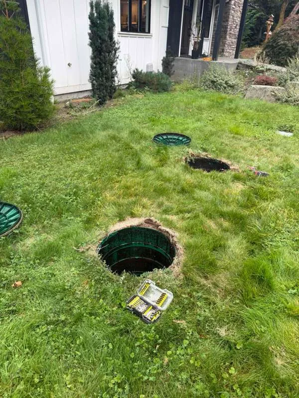 Several riser lids in the lawn, one lifted off, with a tool case beside it.
