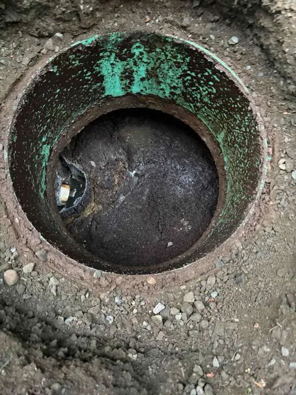 Looking down a riser at the tank before pumping, its surface covered over with solids.
