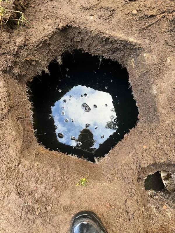 The inlet access open in the dug-out ground, with liquid standing near the top of the tank.