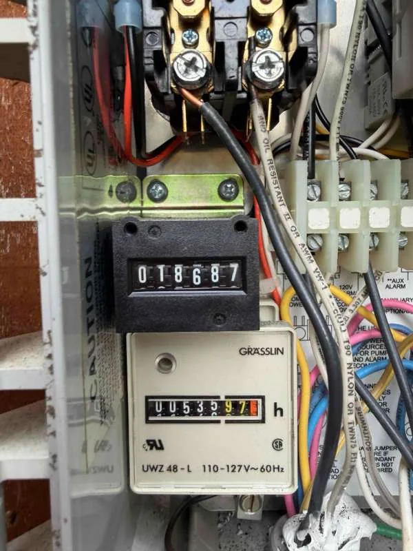 The control panel open, showing the cycle counter and the hour meter above the wiring.