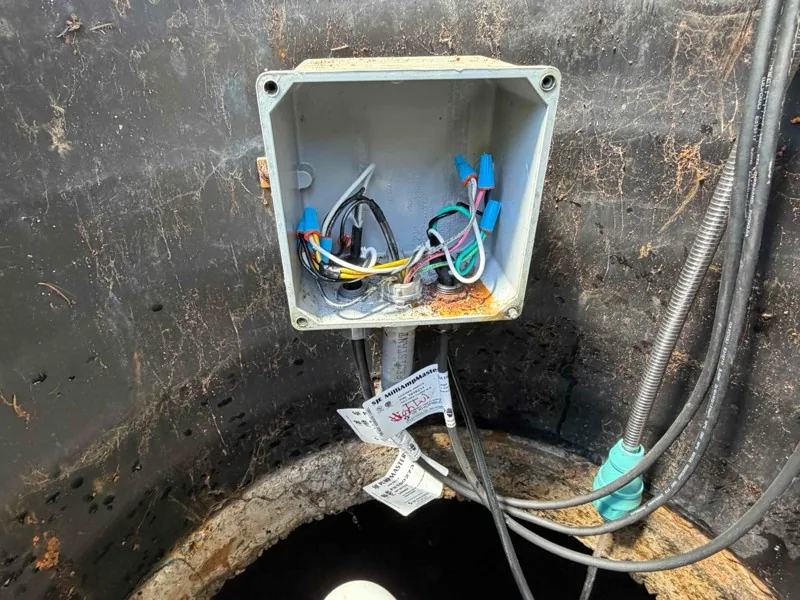 The junction box opened on the riser wall, with the float wiring made up inside.