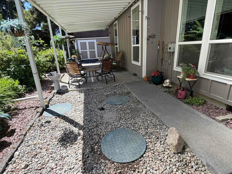 The tank and pump tank lids set in the gravel bed beside the covered patio.