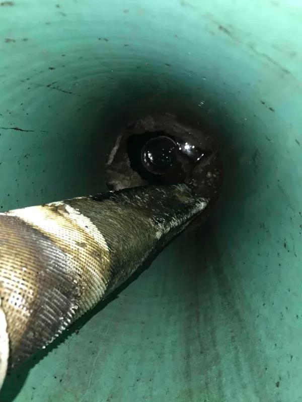 The suction hose worked down through the riser into the tank opening below.