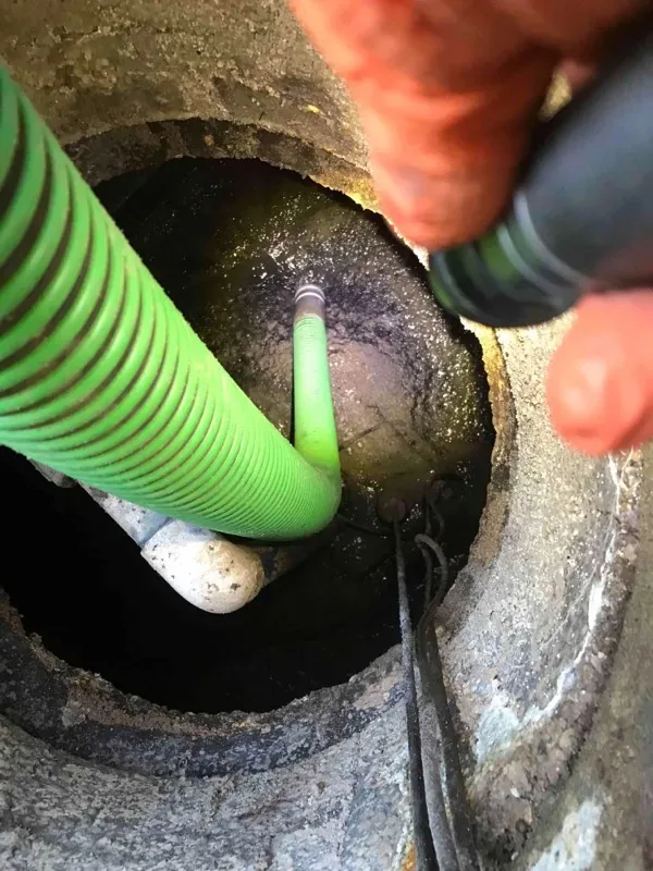 A technician lighting the opening by hand while the suction hose works in the tank.