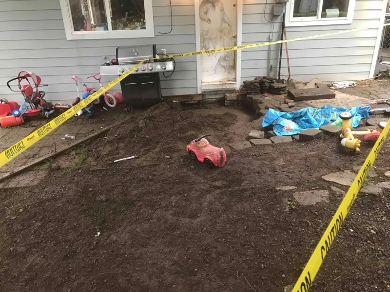 The back yard taped off, with the ground dug over beside the house.