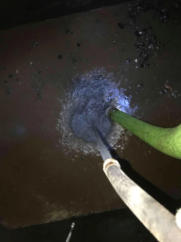 A wand and the suction hose working together in the tank, with the water clouding where they meet.