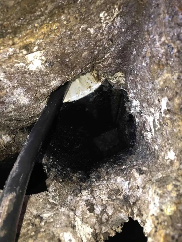 A hose fed through a crusted opening in the tank wall.