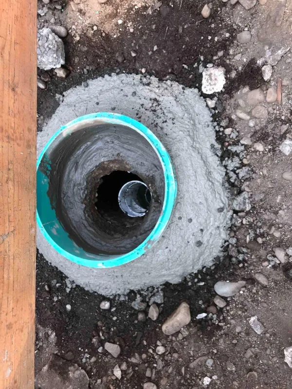 A riser bedded into fresh concrete, with the pipe visible below.