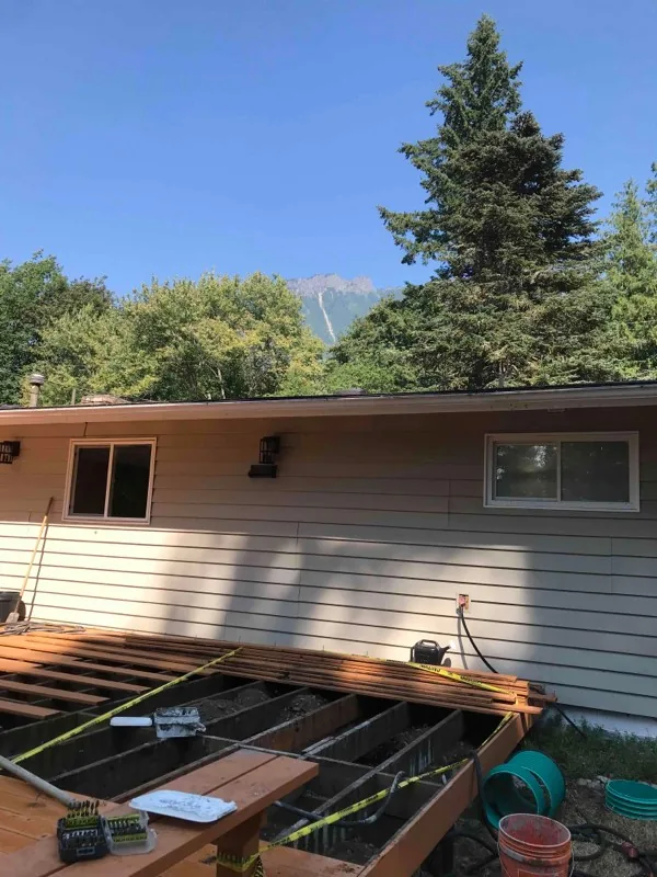 The deck boards lifted along the back of the house, with the work area taped off beneath.