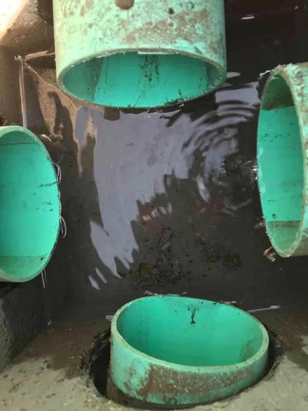 Inside the distribution box, with four pipe stubs set around the chamber and water standing in it.