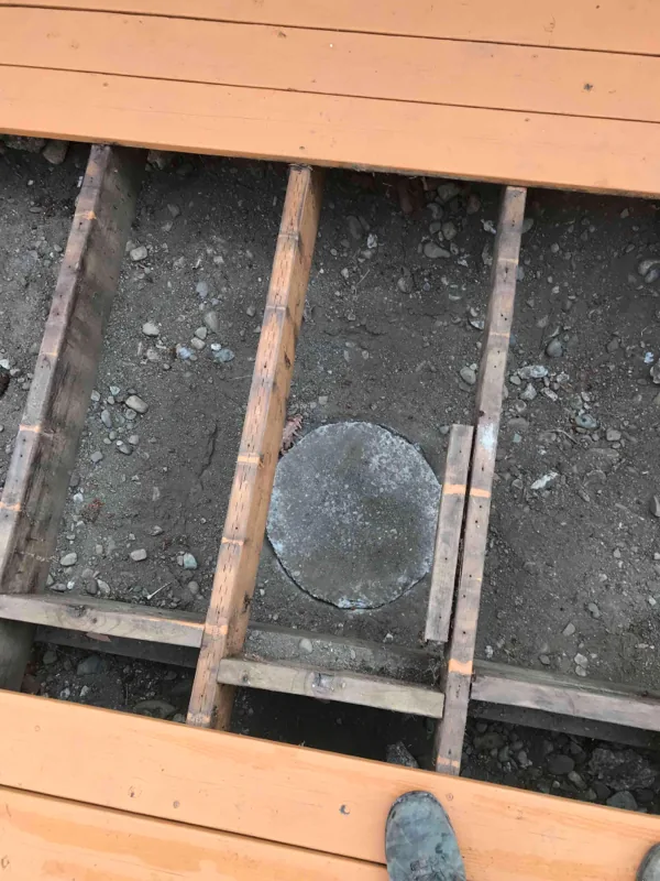 Deck boards lifted to reach the concrete lid in the ground below.
