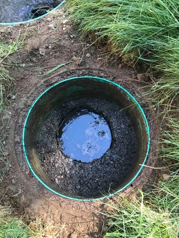 Looking down a riser at standing water over the soil at its base.