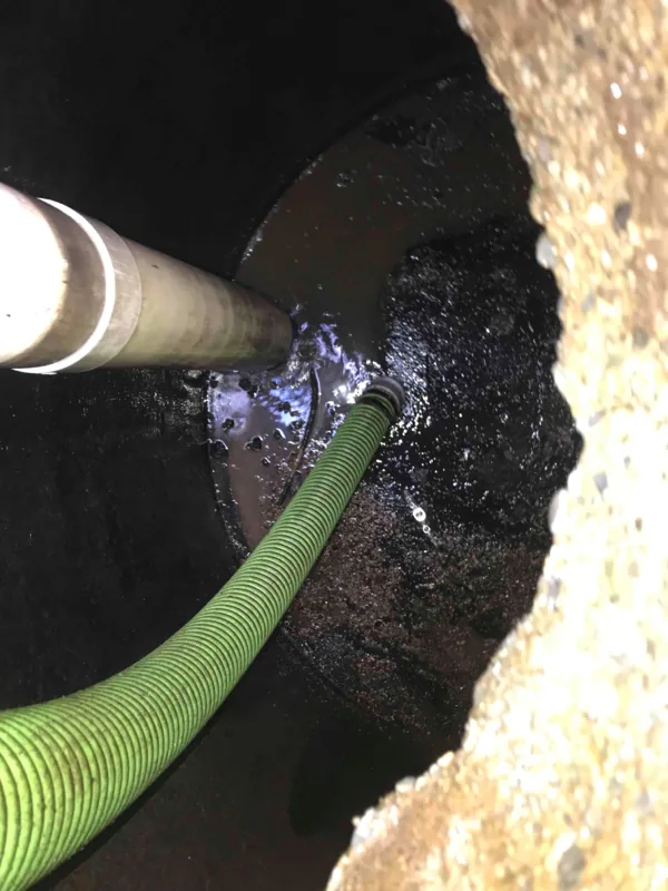 The suction hose run down into the tank alongside the inlet pipe, drawing the contents out.