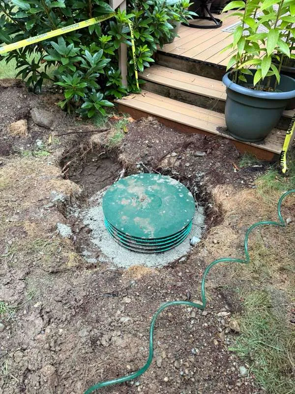 One riser finished, lidded and backfilled, with a gravel collar around it.