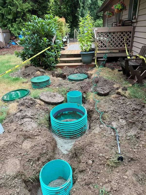 The work area beside the deck, with the tank and its components excavated and the new riser sections in place.