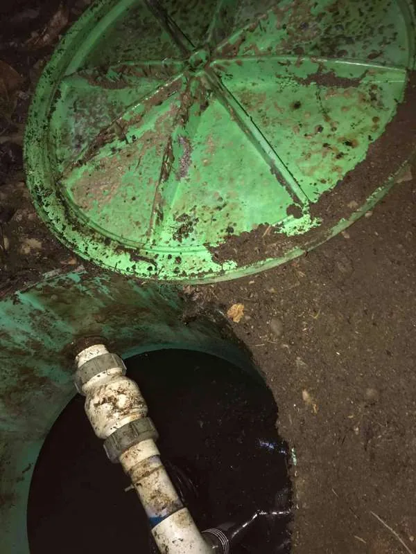 After dark, a lid lifted clear and pipework running down into the tank below.